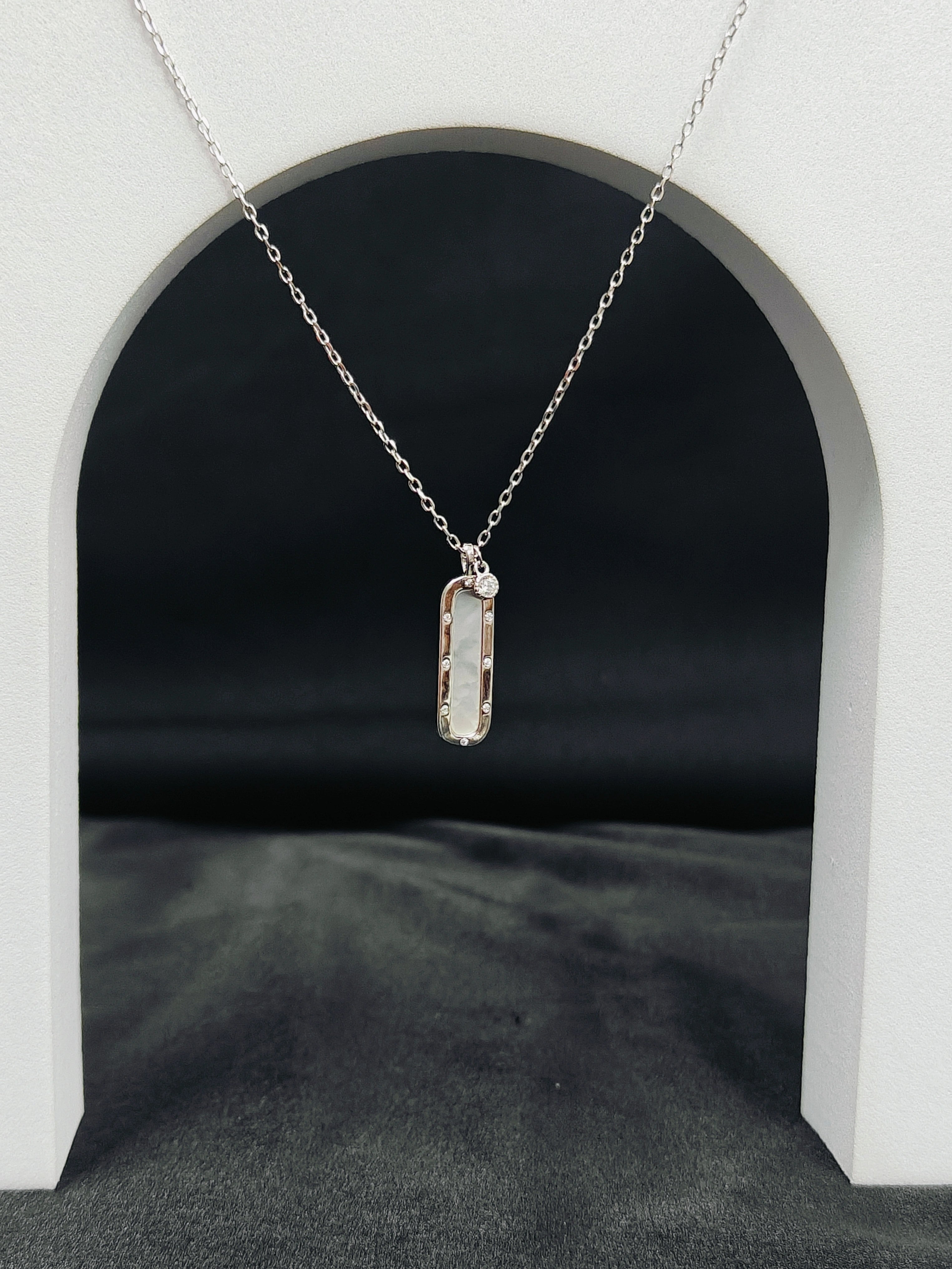 Silver necklace with a rectangular pendant on a black background